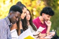 Students sitting on a bench of a park reading notes and studying Royalty Free Stock Photo