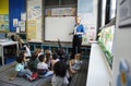 Students sitting on the floor listening to teacher