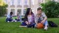 Students sitting on grass near college, acquaintance, first day on campus