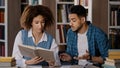 Students studying in library doing homework preparing for exam young girl reads textbook searches information in book Royalty Free Stock Photo