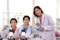 Students and teacher in lab coat have fun together while learn science experiment in laboratory. Young pretty Asian scientist and