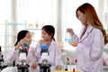 Students and teacher in lab coat have fun together while learn science experiment in laboratory. Young pretty Asian scientist