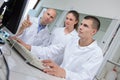 Students and teacher in labcoats loking at computer Royalty Free Stock Photo