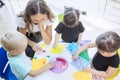 Students and their teacher gluing trinkets on a paper