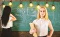 Students and trainees concept. Girl looks confident while lady writing on chalkboard background, defocused. Closeup Royalty Free Stock Photo