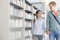 Smiling couple walking while holding hands in library at university Royalty Free Stock Photo