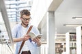 Young student reading book while standing by railing at corridor in university Royalty Free Stock Photo