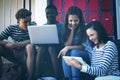 Students using laptop, mobile phone and digital tablet on staircase Royalty Free Stock Photo