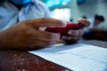 Students using smartphone and doing exam answer sheets exercises in classroom of school Royalty Free Stock Photo