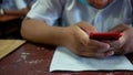 Students using smartphone and doing exam answer sheets exercises in classroom of school Royalty Free Stock Photo