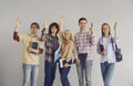 Students vote or are ready to answer questions standing with raised hands on a gray background. Royalty Free Stock Photo