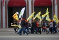 Students walk holding yellow flags.