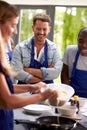 Students Watching Female Teacher Pouring Mixture Into Pan In Cookery Class