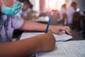 Students wearing mask for protect corona virus or covid-19 and doing exam in classroom with stress Royalty Free Stock Photo