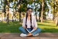 Studentship concept. Happy indian student girl doing homework, holding workbook while sitting on bench in park outdoors Royalty Free Stock Photo