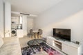 Studio apartment with a combined kitchen and living room with a corner sofa, tables and chairs and a TV with a picture
