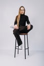 Studio candid unaltered portrait of young blonde woman with long hair sitting on chair. Portrait of Fashionable stylish