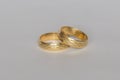 Two gold wedding bands with engraved pattern, classic marriage rings close up on light background Royalty Free Stock Photo
