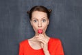 Portrait of surprised amazed girl sucking pink lollipop