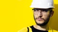 Studio close-up portrait of young confident man architect, builder engineer, wearing white construction safety helmet. Royalty Free Stock Photo