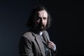 Studio dramatic of a young bearded and curly-haired guy of thirty years, in an expensive business suit, holds his hand by the Royalty Free Stock Photo