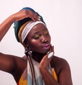 Studio fashion portrait of young African woman in summer dress and ethnic head wrap, white background