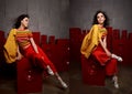 Studio fashion shooting. The girl in a bright outfit, top and pants flared in red and orange tones. Brunette with curly Royalty Free Stock Photo