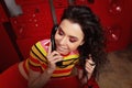 Studio fashion shooting.The girl in a bright outfit, top and pants flared in red and orange tones. Brunette with curly Royalty Free Stock Photo