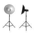 Studio flash lights with reflectors on tripods against white background Royalty Free Stock Photo