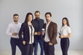 Group portrait of serious young business people standing in studio looking at camera