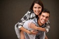 Studio, hug and portrait of happy couple, piggyback ride and having playful fun together on brown background. Wellness Royalty Free Stock Photo