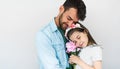 Studio image of handsome father hold embraces his cute daughter and giving her a pink flower. Loving daddy and his little girl