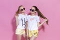 Studio lifestyle portrait of pretty two best friends sister girls, posing and having fun together at pink background Royalty Free Stock Photo