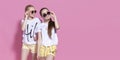 Studio lifestyle portrait of pretty two best friends sister girls, posing and having fun together at pink background Royalty Free Stock Photo