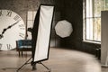 Studio light in a decorated photo studio. There`s a big watch and a sofa in the background. Grey interior. High quality