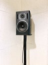 A studio monitor, high-quality speaker on the steel stand with the acoustic board, sound absorption wall as the white background.