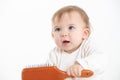 Studio photo with a white background of a baby with a comb in his hand