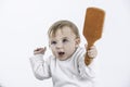 Studio photo with a white background of a baby with a comb in his hand