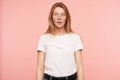 Studio photo of young amazed long haired redhead lady rounding surprisedly her green eyes while looking at camera, over