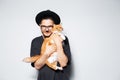 Studio photo of young attractive man in black hat, holding a cute red cat. Royalty Free Stock Photo