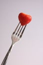 A fresh strawberry and a fork against a white background Royalty Free Stock Photo