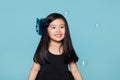 Studio portrait of asian girl with soap bubbles in front of blue background Royalty Free Stock Photo