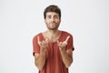 Studio portrait of attractive bearded student in red t-shirt stretching his hands to the camera. Emotional man with