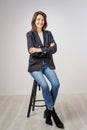 Smiling brunette haired woman wearing blazer and jeans and standing at isolated background Royalty Free Stock Photo