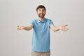 Studio portrait of attractive young male speaker stretching arms towards camera as if talking with audience, expressing Royalty Free Stock Photo