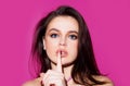 Studio portrait of beautiful elegant woman. Young lady showing shhh taboo sign with finger to lips over pink background Royalty Free Stock Photo