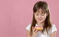 Studio portrait of a beautiful little girl holding a donut and smelling tasty flavour Royalty Free Stock Photo