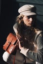 Studio portrait of beautiful woman with a curly blond hair holding brown bag, posing on gray background.