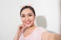 Studio portrait of beautiful woman smiling with white teeth and making selfie, photographing herself over white background