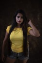 Studio portrait of a beautiful and young Indian Bengali female model in yellow tee shirt and jeans hot pat Royalty Free Stock Photo